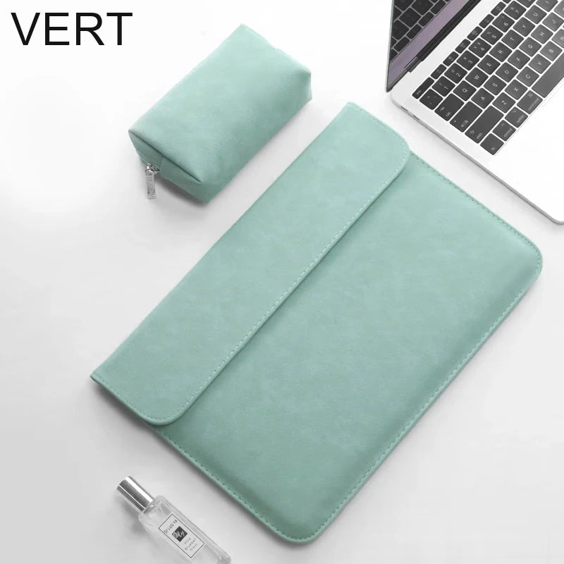 Pochette ordinateur vert d'eau en simili cuir, rabat fermé, posée en biais sur un bureau avec sa trousse assortie.