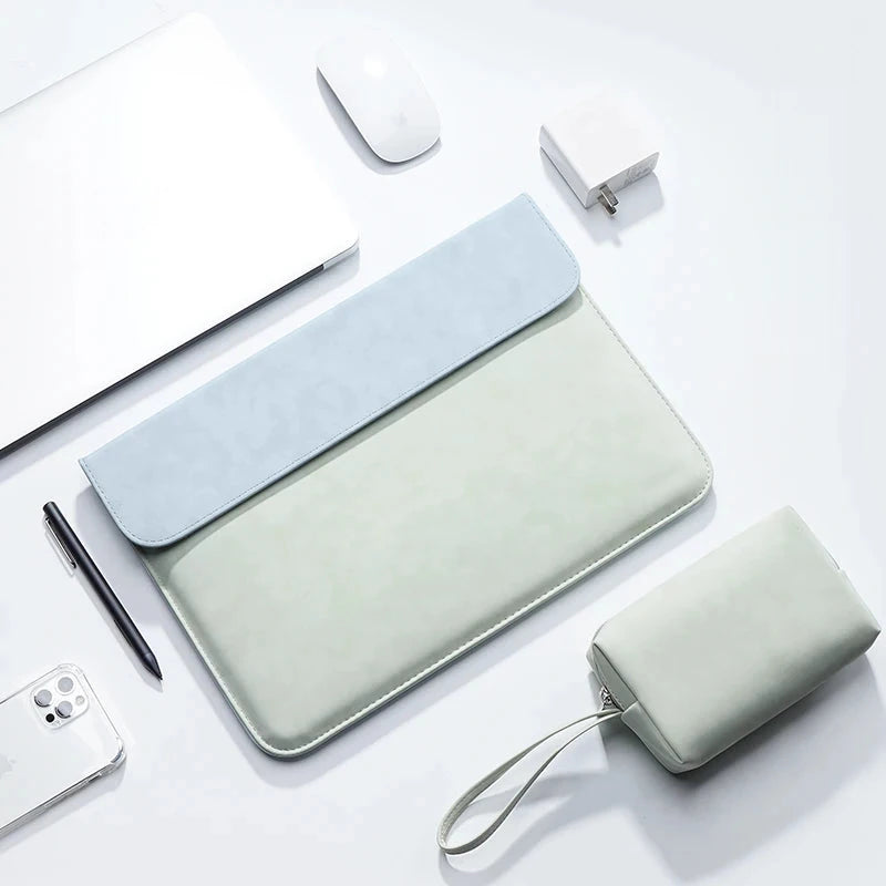 Pochette ordinateur vert amande à rabat bleu clair, vue de dessus sur un bureau blanc avec sa trousse assortie.