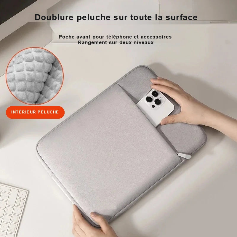 Pochette d'ordinateur portable grise avec doublure peluche, posée sur un bureau, une main y glissant un smartphone dans la poche avant ; médaillon détail sur la texture peluche intérieure.