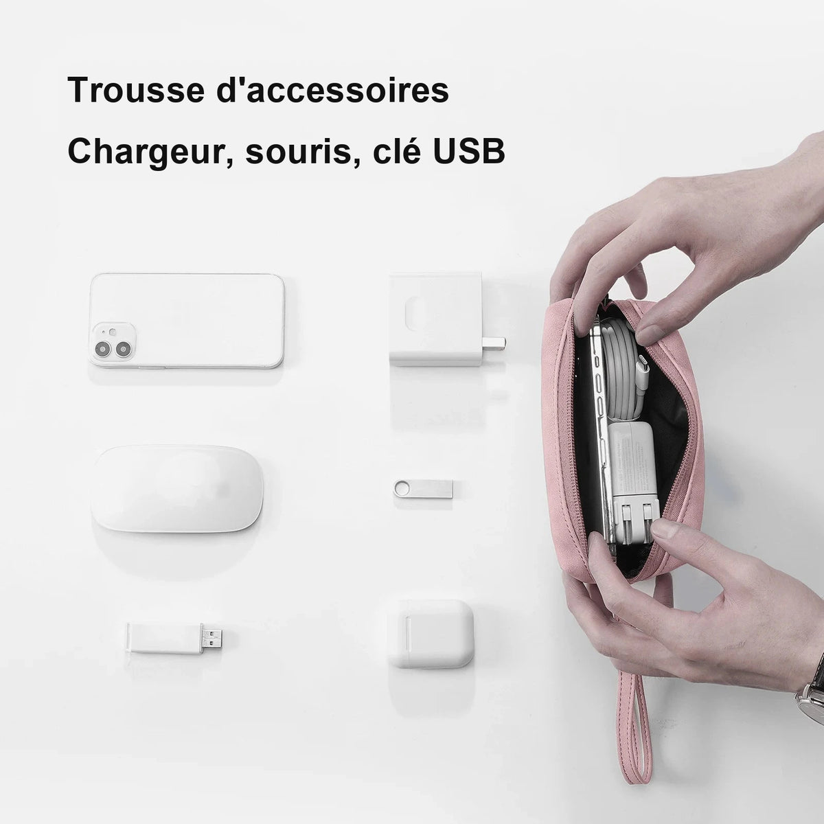 Trousse rose ouverte à deux mains, garnie d'un chargeur et d'un câble enroulé, posée près d'un téléphone, d'une souris, d'une clé USB et d'un boîtier d'écouteurs.