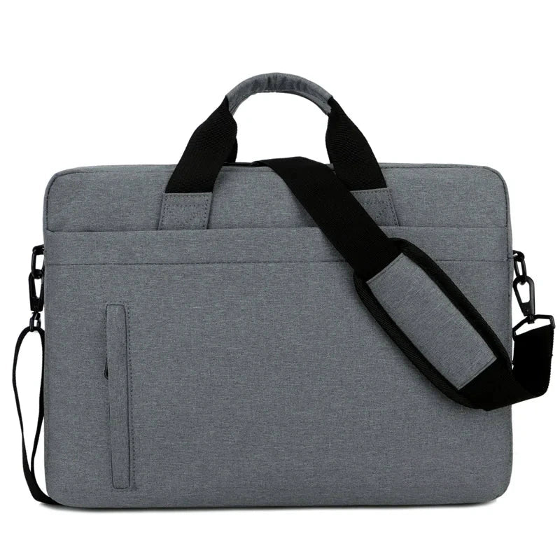 Sacoche pour ordinateur portable grise avec poignée et bandoulière noires rembourrées, poche avant zippée et porte-stylo, présentée sur fond blanc.