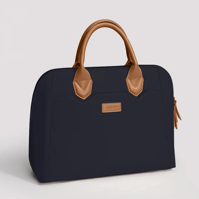 Sacoche ordinateur bleu marine avec poignées et anses en cuir tan, étiquette en cuir sur la face avant.