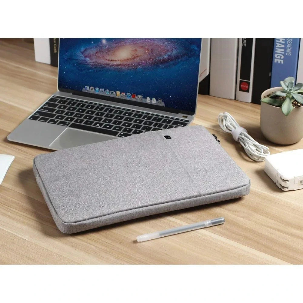 Pochette rembourrée en tissu gris chiné posée sur un bureau en bois clair, devant un ordinateur portable ouvert, un câble enroulé et une plante grasse.
