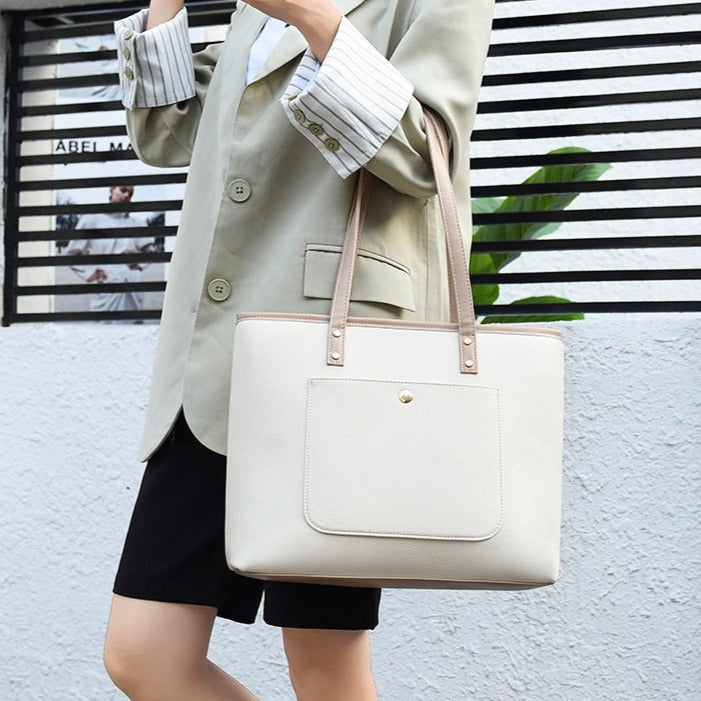 Femme en blazer beige portant un grand sac cabas blanc à anses en cuir rose pâle