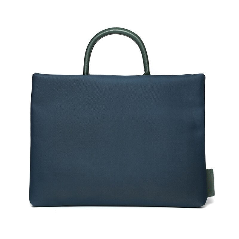 Sacoche bleu marine pour ordinateur portable, poignée arrondie et languette latérale vert foncé, vue de face sur fond blanc.