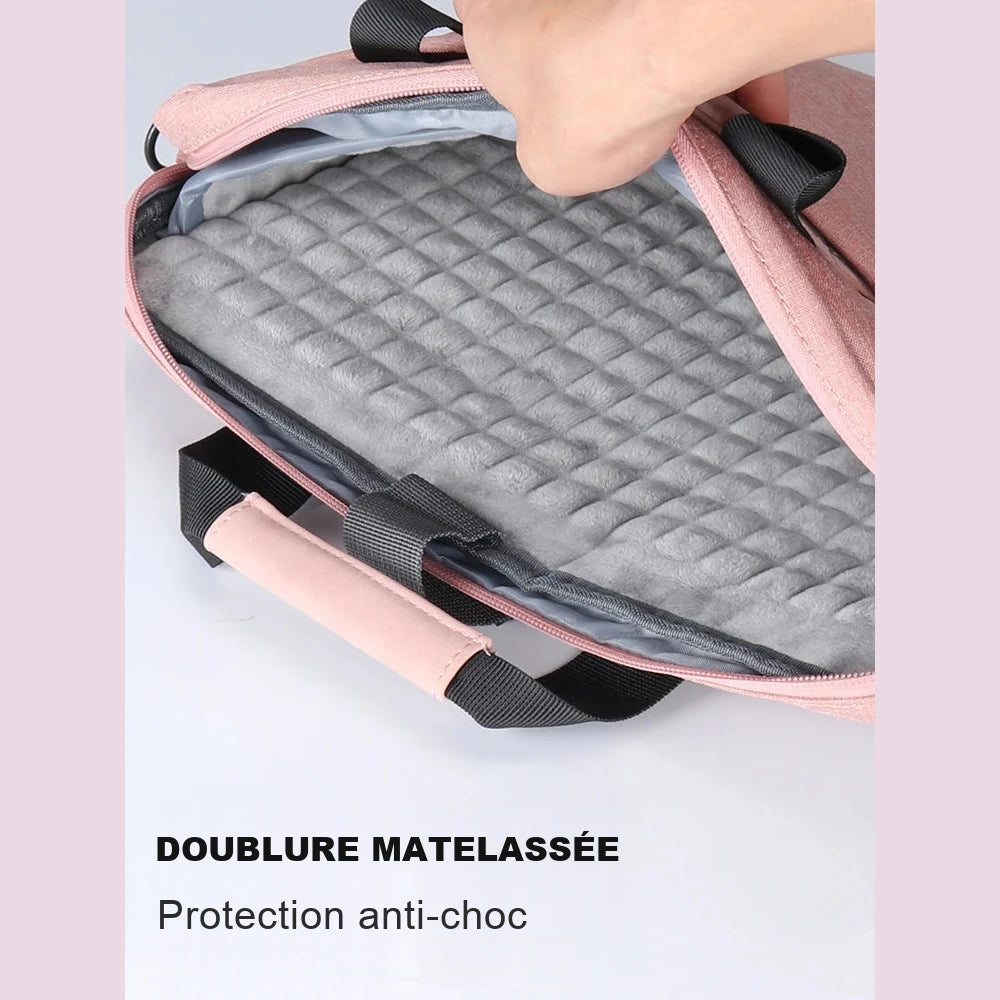 Intérieur d'une housse d'ordinateur rose ouverte à la main, montrant la doublure grise matelassée.