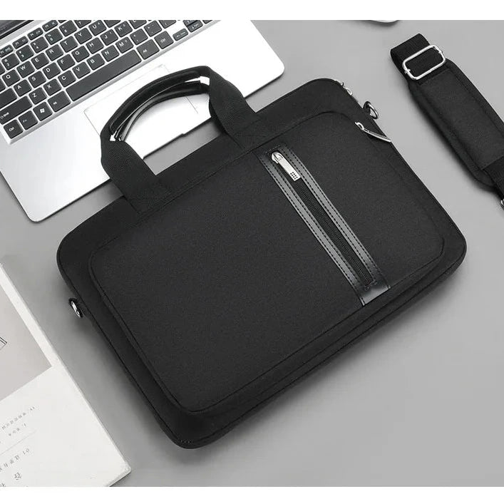 Sacoche noire pour ordinateur portable posée sur un bureau, poignées rigides, poche zippée sur le devant et bandoulière matelassée à côté.