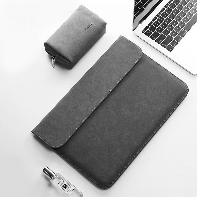 Pochette ordinateur 14 pouces en simili cuir gris foncé, posée sur un bureau