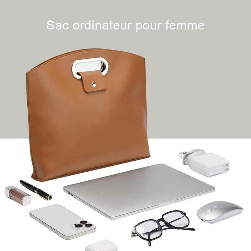 Sac ordinateur cognac posé debout, vu de face, entouré d'un ordinateur portable, d'une souris, d'un téléphone et de lunettes.